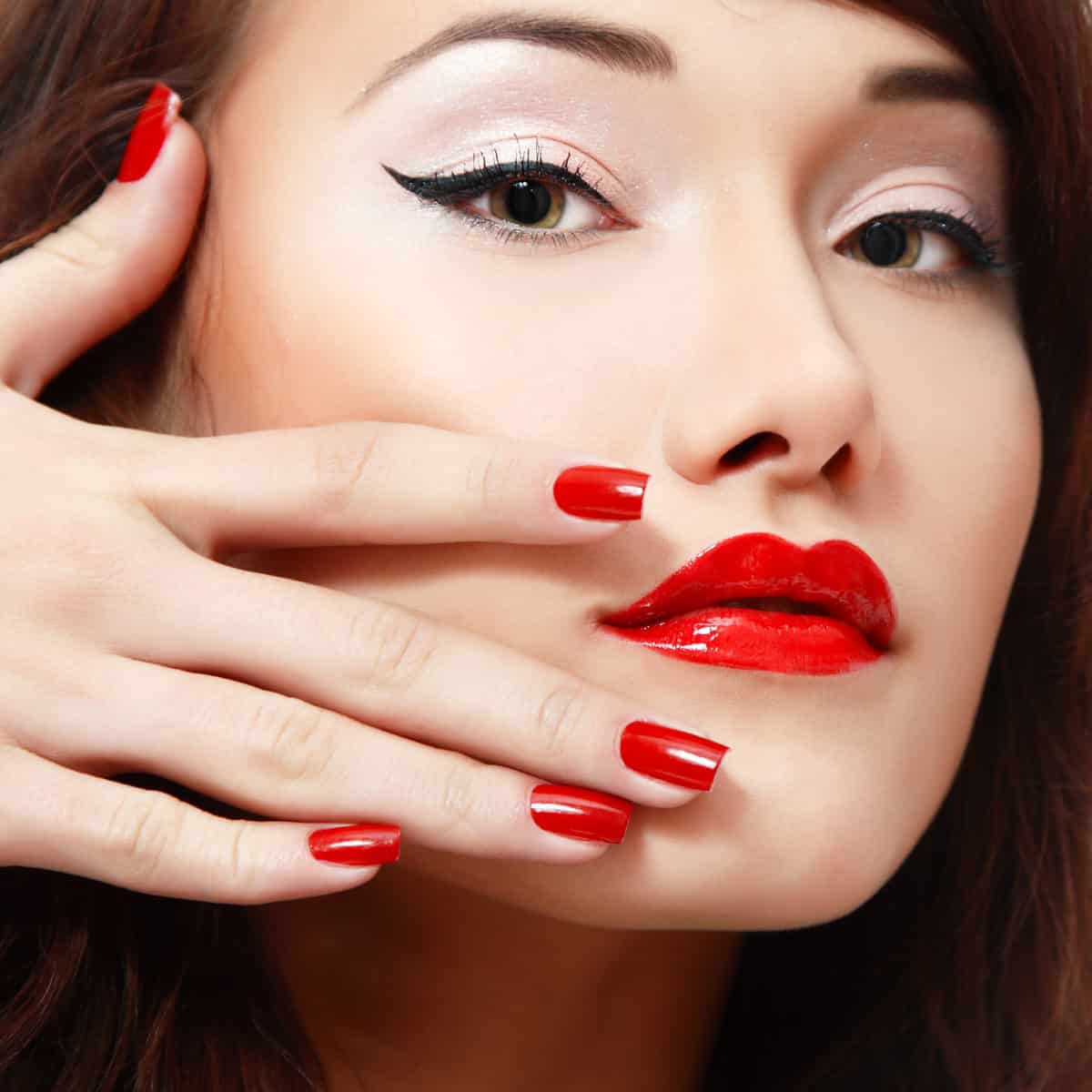 beautiful young female face with vivid red lipstick and nail pol