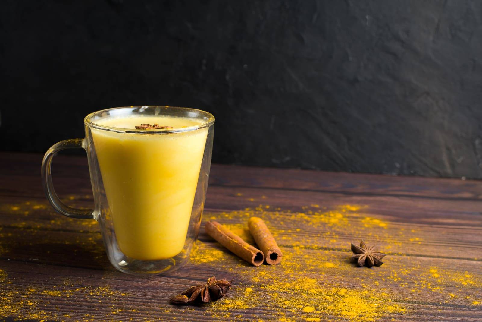 Golden turmeric milk drink with turmeric powder and ingredients