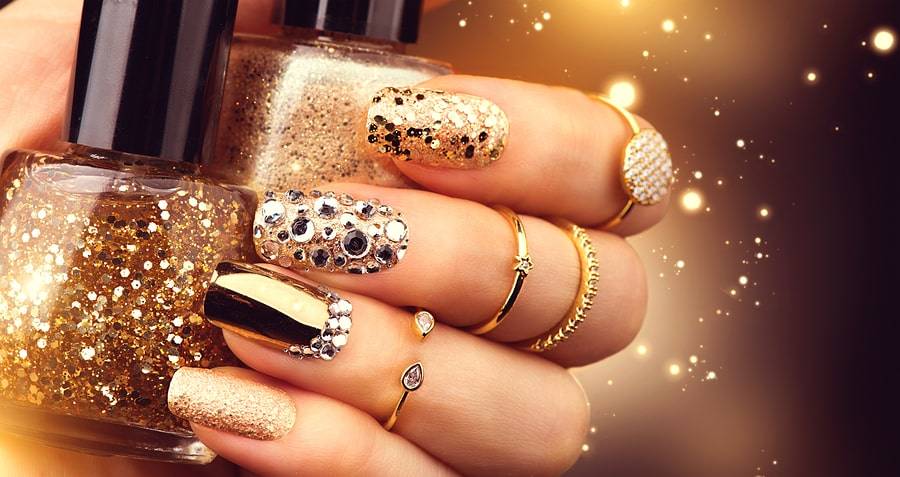 Golden Nail art manicure. Holiday style bright Manicure with gems and sparkles. Bottle of Nail Polish. Fashion rings with diamonds, Trendy Accessories. Beauty hands. Stylish Nails, Nailpolish