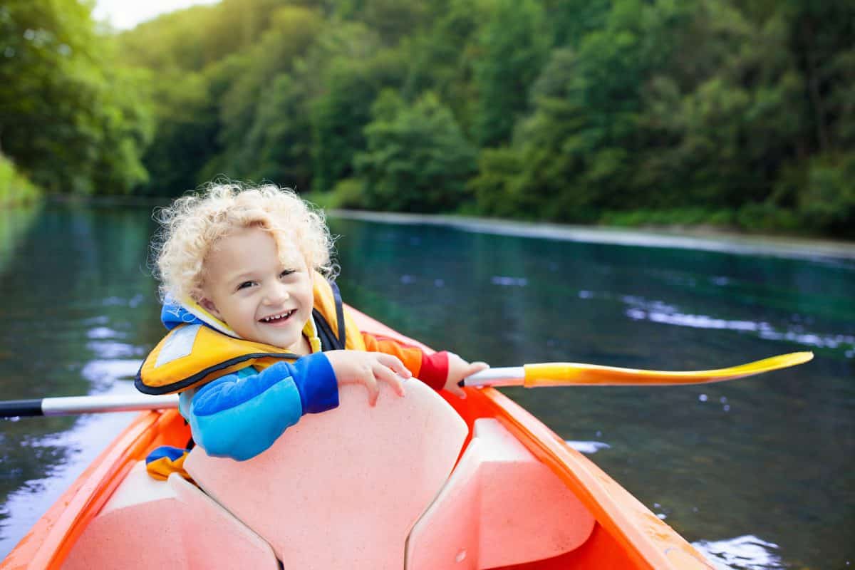 Child with paddle on kayak.