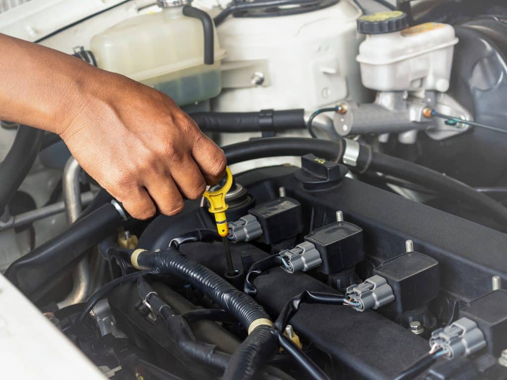 Technician hand opening the car oil tank lid for checkin