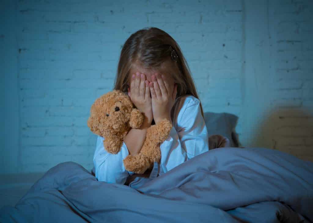 Scared little girl sitting in bed