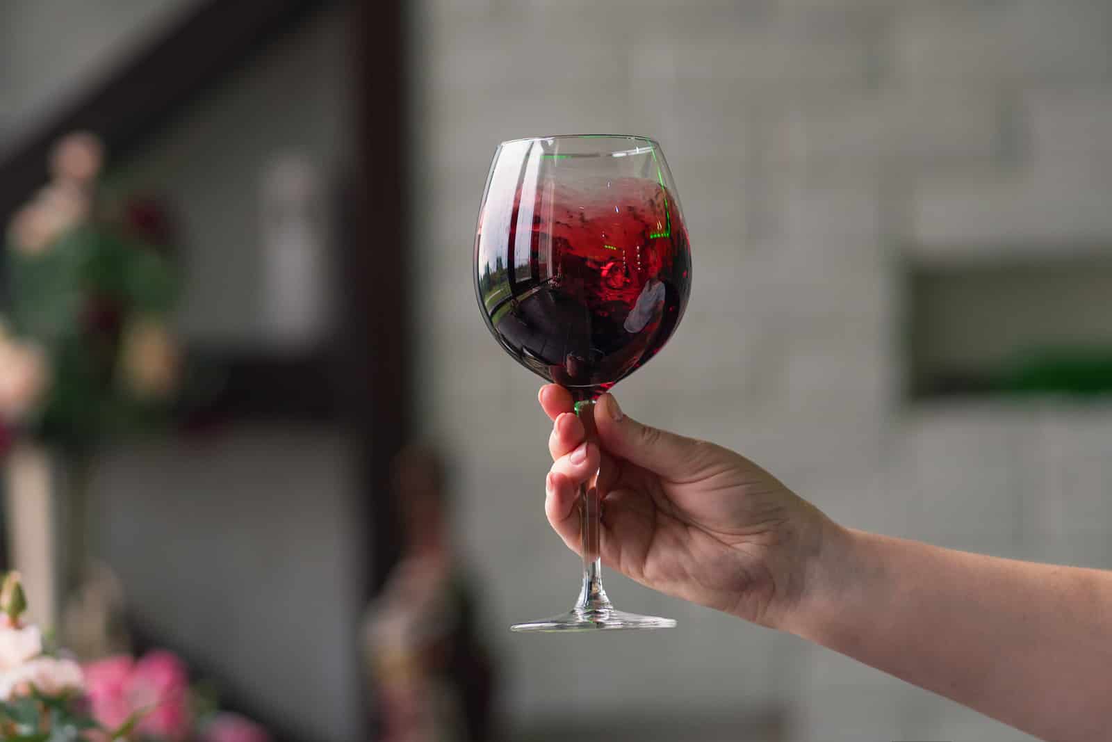 Hand sommelier holding glass of red wine. Mothers day gift