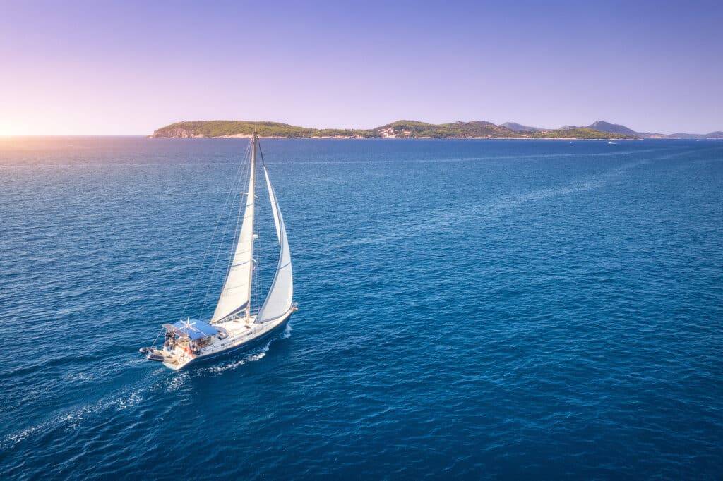 Aerial view of beautiful white sailboat in blue sea