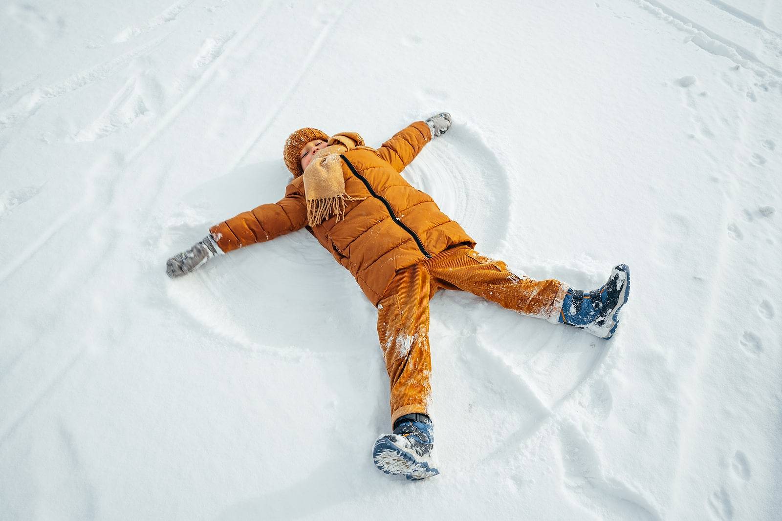 Kid making a snow angel in winter park