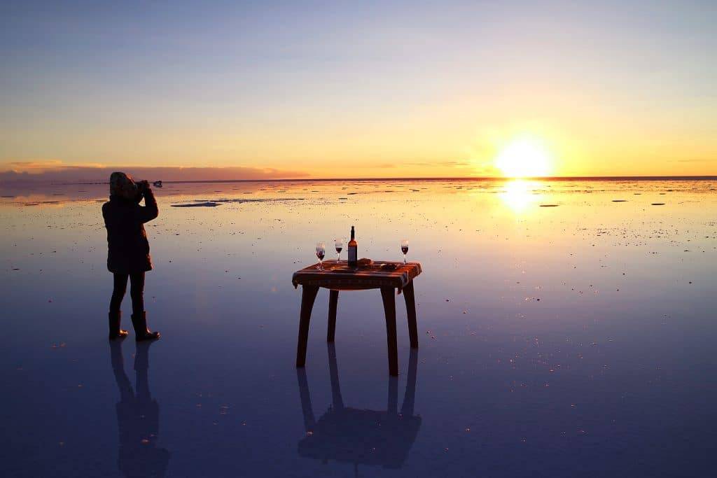 Traveler Celebrating on the Flooding Salt Flats, the Iconic Mirror Effect of Salar de Uyuni at Stunning Sunset, Potosi Department, Bolivia, South America